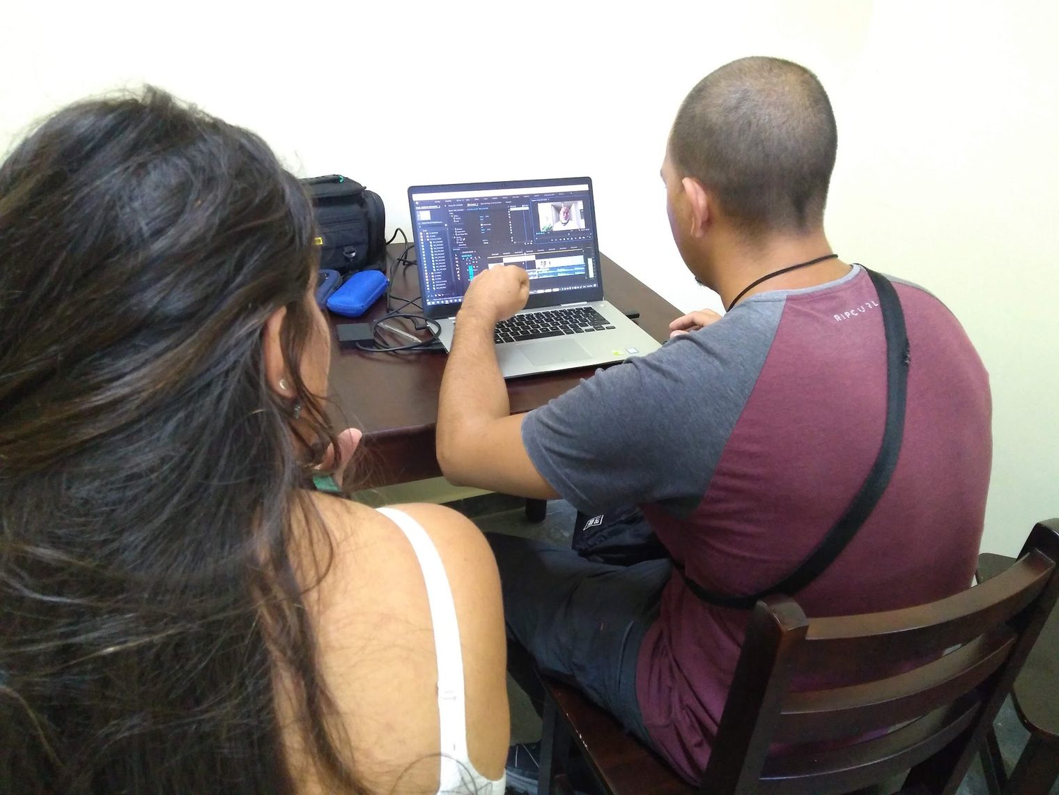 Two members of the collaborative coverage team, seen from behind, editing the seminar video on a laptop