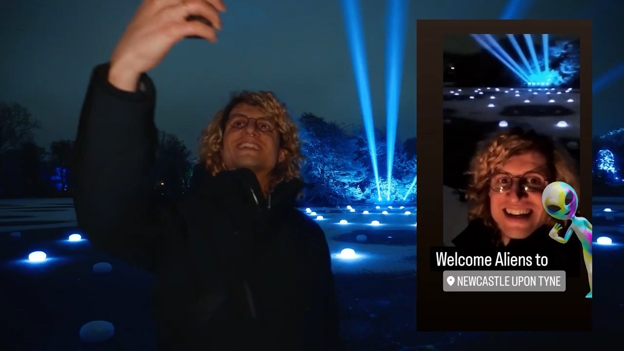 Still from Any Plans: Joe takes a selfie under blue light beams at night, his story reading "Welcome Aliens to Newcastle upon Tyne"