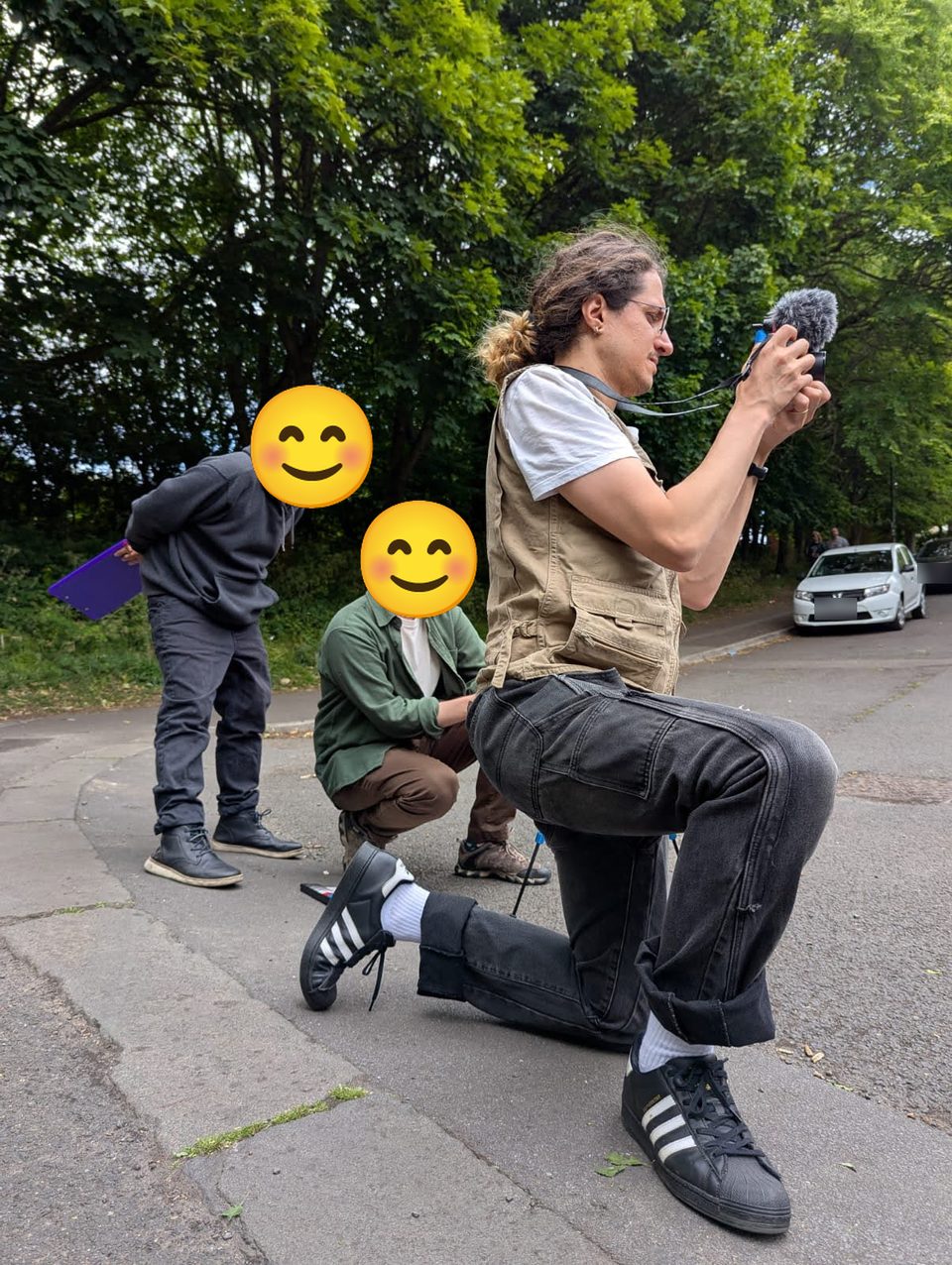 João Lazaro kneeling on a Newcastle street to film with a camera and microphone, two crew members watching, behind the scenes of To say 'I love you' is my favourite drug